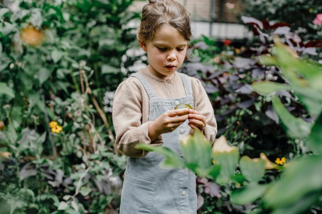 A child holding a fruit in a garden