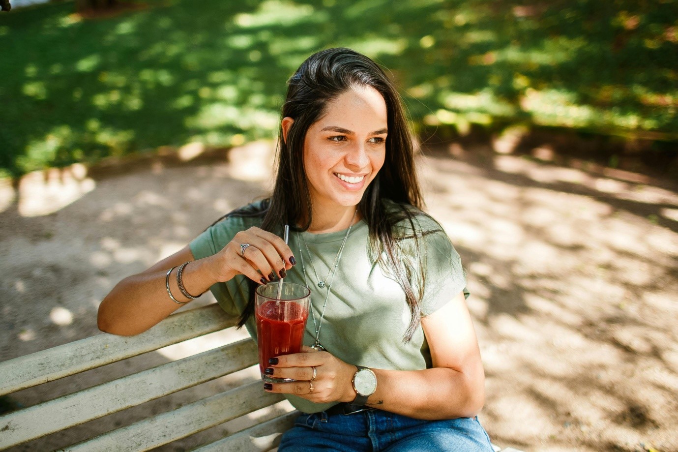 A person having a drink while sitting on a bench