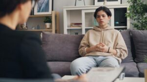 Patient sitting on a couch speaking during a mental health consultation