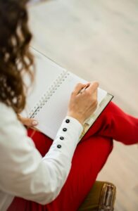 Person sitting and writing in a notebook, organizing thoughts during a quiet moment