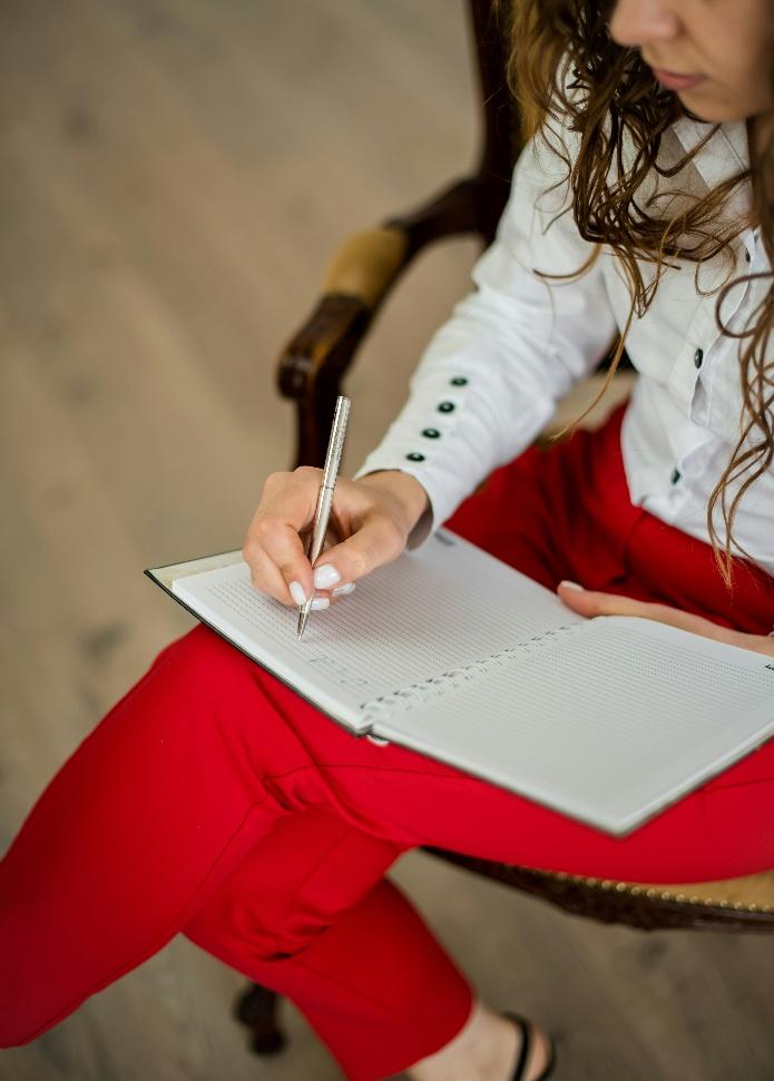 Woman sitting and writing in a notebook, organizing thoughts and tasks